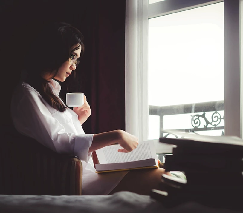 woman reading Bible by window quiet time with God deepening faith