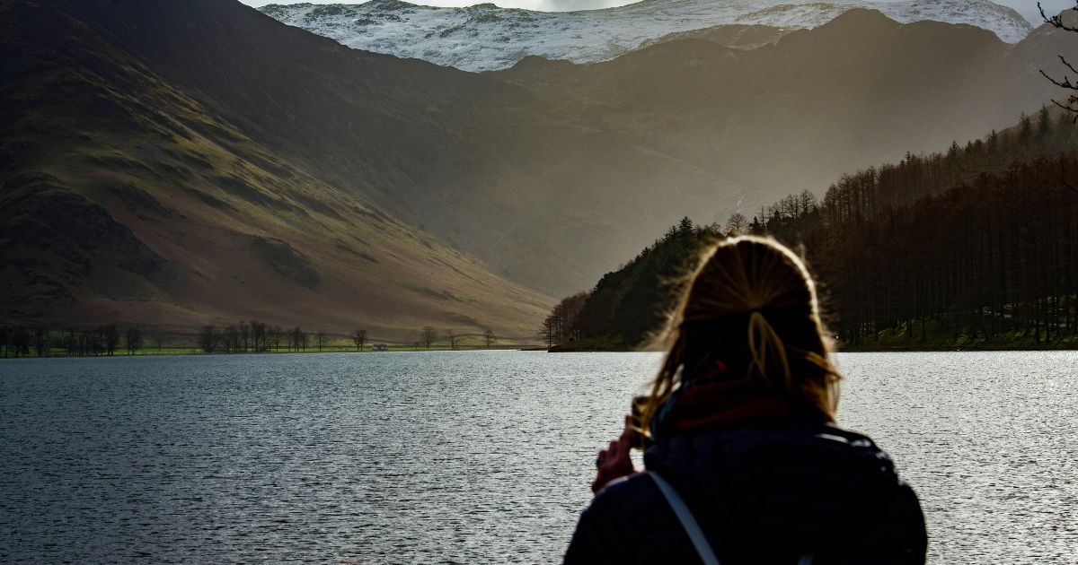 Woman looking across a mountain lake, symbolizing overcoming fear, trusting God, and walking in freedom through faith.