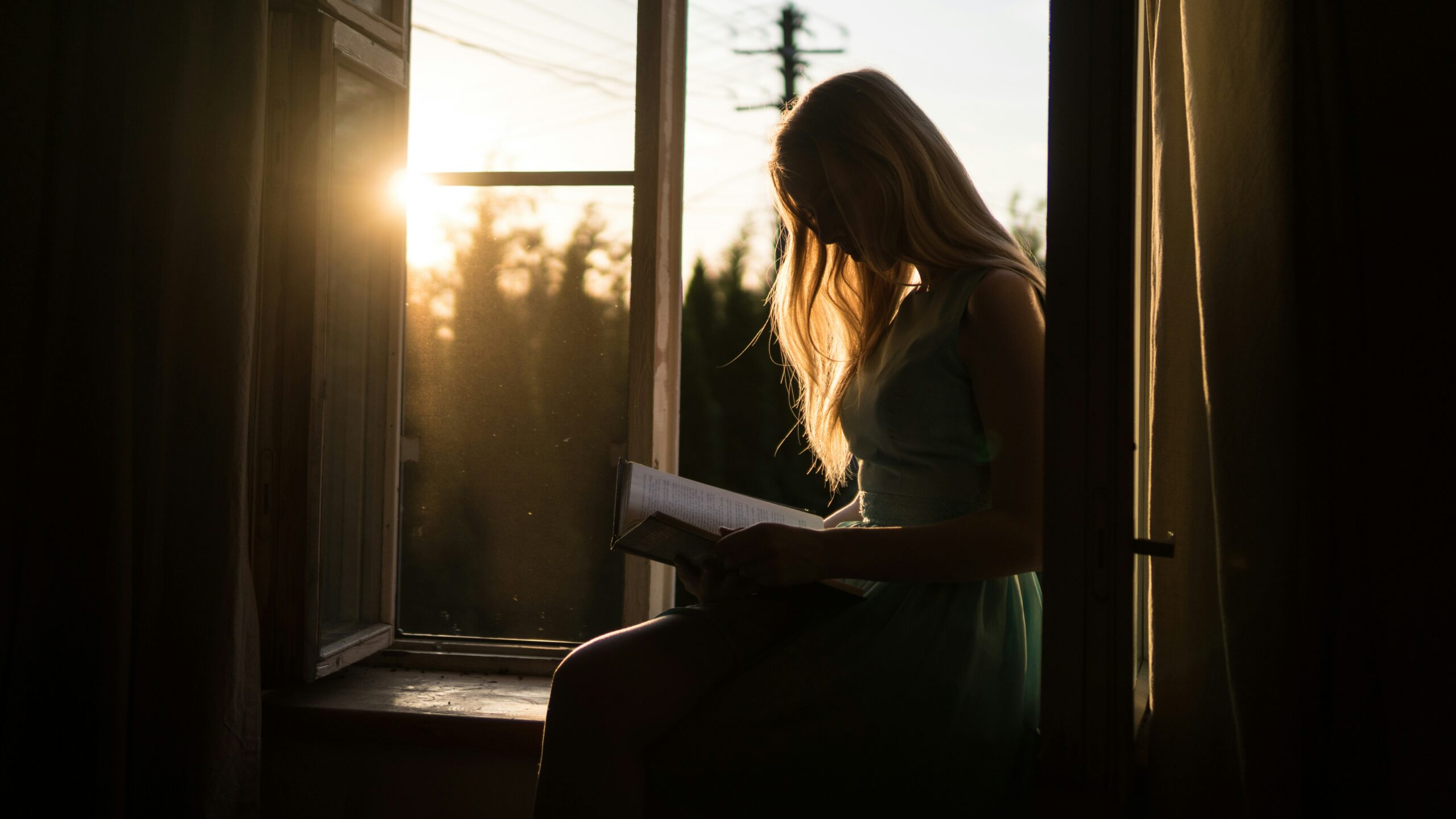 Woman reading the Bible at sunrise while seeking to Recognise God's Voice